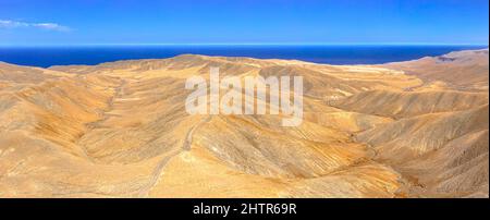 Vue aérienne d'une route vide traversant les montagnes désertiques vers l'océan Atlantique bleu, Fuerteventura, îles Canaries, Espagne Banque D'Images