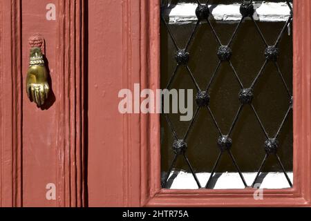 Ancienne maison néoclassique porte en bois brun rougeâtre avec grilles en fer forgé fabriquées à la main et un ancien knocker en laiton à Nafplio, Grèce. Banque D'Images