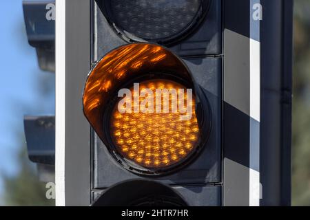 Feu de circulation avec lumière orange contre le ciel du soir. Banque D'Images