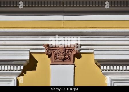 Ancienne façade de maison néoclassique avec un mur en stuc ocre, des colonnes d'ordre ionique et une garniture en plâtre blanc à Nafplio, Grèce. Banque D'Images