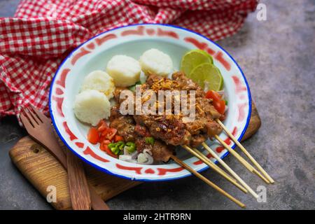 Cuisine indonésienne célèbre : sate ayam (poulet satay), servi avec une sauce aux arachides et un gâteau de riz ou lontong Banque D'Images