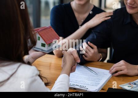 Un jeune couple heureux reçoit une merveilleuse affaire après avoir signé un contrat pour acheter une maison. Le courtier et le client se bousculer après avoir fait une bonne affaire Banque D'Images