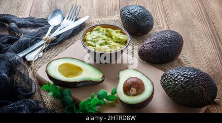 Bol avec trempette guacamole et avocats sur une table en bois Banque D'Images