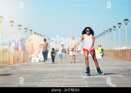 L'air frais et les rollerblades me permettent de commencer ma journée. Photo d'une jeune femme attirante en roller sur une promenade. Banque D'Images