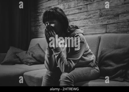 Triste jeune femme assis et pleurant seul à la maison, des problèmes de relations ou des troubles psychologiques et mentaux de seule jeune fille. Photo en noir et blanc. Banque D'Images