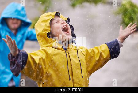 Ils aiment la pluie. Photo d'un jeune frère et d'une sœur jouant sous la pluie. Banque D'Images