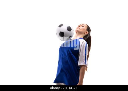 Une jeune joueuse de football caucasienne frappe le ballon de football avec la poitrine tout en jouant au football Banque D'Images