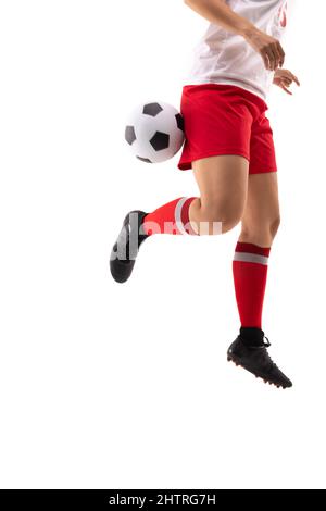 Coupe basse de la jeune femme biracial qui donne un coup de pied au ballon de football avec talon arrière tout en jouant au football Banque D'Images