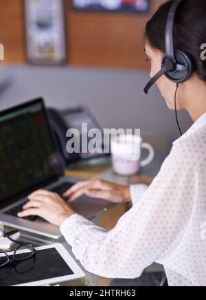 En cours d'appel. Photo d'une jeune femme d'affaires attirante travaillant sur un ordinateur portable tout en portant un casque. Banque D'Images