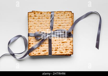 matza à pain plat juif pour la Pâque avec ruban sur fond blanc Banque D'Images