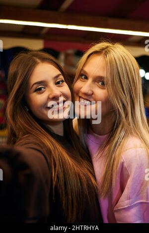 Deux jeunes femmes souriant et prenant un selfie la nuit Banque D'Images
