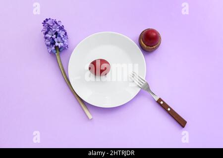 Table avec œufs de Pâques et fleurs sur fond lilas Banque D'Images