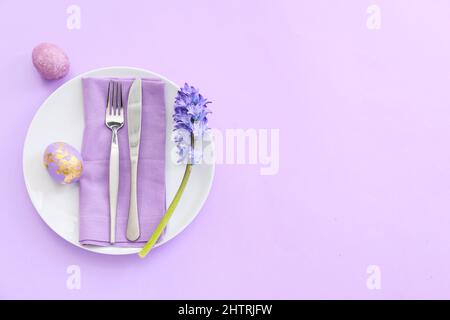 Belle table avec œufs de Pâques et fleurs sur fond lilas Banque D'Images