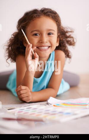 Les arcs-en-ciel sont ma chose préférée dans le monde entier. Photo d'une petite fille peignant une photo d'un arc-en-ciel. Banque D'Images
