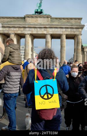 Homme avec packard sur son dos. Panneau Pacifique avec texte anglais pas de guerre sur drapeau bleu jaune ukrainien. Manifestation anti-guerre en Ukraine dans la capitale allemande. Banque D'Images