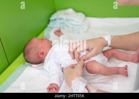 les mains d'une mère qui vient de donner naissance à l'hôpital avec le bracelet d'identification de l'hôpital et la ligne de médicaments sur son poignet mettent une dbo Banque D'Images