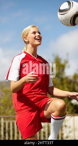 Shes de mieux en mieux. Prise de vue d'une joueuse de football se lançant autour d'une balle de football. Banque D'Images