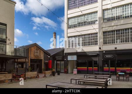 La cour de la Custard Factory, Digbeth Birmingham, avec la fresque Alfie Mo sur la grande cheminée en briques de 30m en arrière-plan. Banque D'Images