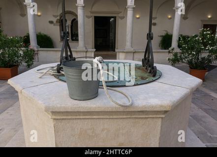 Piran, Slovénie - 25 août 2021 : une fontaine dans le monastère, avec un seau comme installation dans le jardin intérieur Banque D'Images