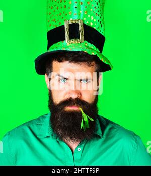 Patrick. Homme barbu dans le chapeau de lepreun avec Clover dans la bouche. Vacances de printemps traditionnelles irlandaises. Banque D'Images