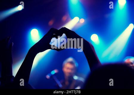 Une jeune personne montrant l'amour et la lumière au groupe sur scène. Ce concert a été créé dans le seul but de cette séance photo, avec 300 modèles Banque D'Images