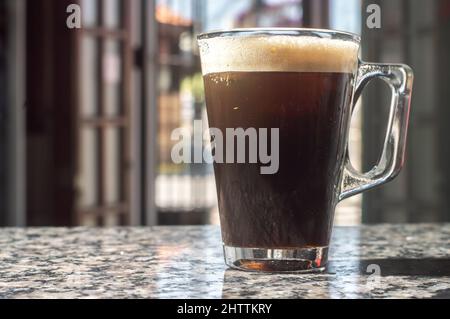 café tonique dans une tasse transparente qui est sur une table marmore, le climat urbain en arrière-plan. Banque D'Images