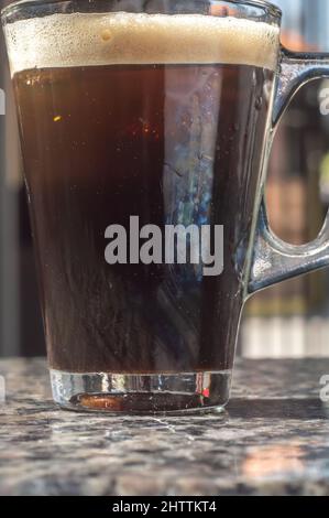 café tonique dans une tasse transparente qui est sur une table marmore, le climat urbain en arrière-plan. Banque D'Images