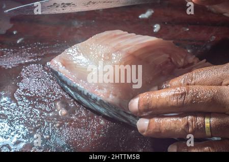Comment racler le tilapia poisson à l'aide d'un couteau, homme essuyant un poisson sur une table en bois. Banque D'Images