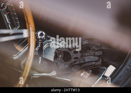 Photo de mise au point peu profonde de gants en cuir noir à côté du bouton de changement de vitesse dans la voiture Banque D'Images