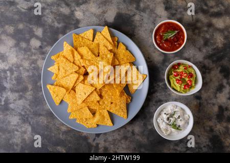 Vue en hauteur des chips nacho dans l'assiette par diverses sauces à trempette servies sur la table Banque D'Images