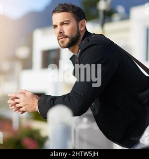 Le mystère de l'esprit masculin. Photo d'un jeune homme bien pensé, penché contre une rampe extérieure. Banque D'Images