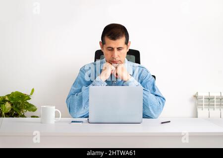Photo courte d'un beau jeune homme d'affaires assis dans son bureau à domicile et regardant contemplatif tout en travaillant sur son ordinateur portable Banque D'Images