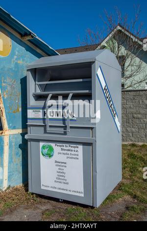 Nova Bana, Slovaquie - Fébuary, 27, 2022 : conteneur Humana pour vêtements, chaussures, sacs, ceintures et textiles usagés. Personnes aidant d'autres personnes concept.