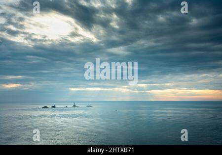 Vue depuis le célèbre point de repère le plus à l'ouest de la Grande-Bretagne et de la côte cornish, Longships Lighthouse entouré par un océan Atlantique calme en été, couche de mince Banque D'Images