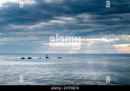 Vue depuis le célèbre point de repère le plus à l'ouest de la Grande-Bretagne et de la côte cornish, Longships Lighthouse entouré par un océan Atlantique calme en été, couche de mince Banque D'Images