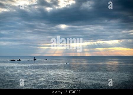 Vue depuis le célèbre point de repère le plus à l'ouest de la Grande-Bretagne et de la côte cornish, Longships Lighthouse entouré par un océan Atlantique calme en été, couche de thi Banque D'Images