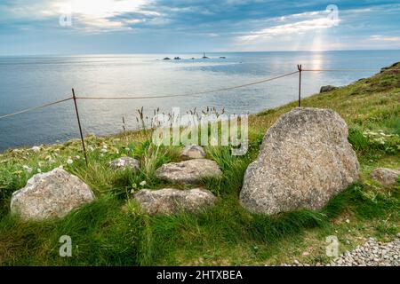 Piercing été rayons de soleil couchant, vue sur le sommet de la falaise du célèbre point de repère le plus à l'ouest de la Grande-Bretagne, une destination touristique populaire, Longships Lighthouse Banque D'Images