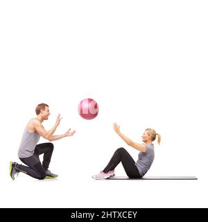 Sensation de brûlure. Un homme et une femme exerçant leur abs en passant une balle de médecine les uns aux autres. Banque D'Images