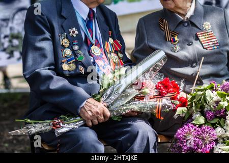 Dire Au revoir à un ami cher. Image rognée de deux anciens combattants de guerre tenant des fleurs à un enterrement. Banque D'Images