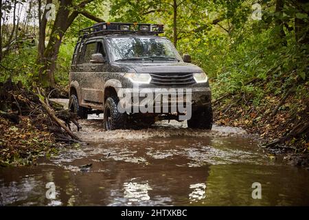 Région de Moscou, Russie - 28.09.2018. Tout-terrain sur un camion noir UAZ Patriot. La voiture roule le long d'un ruisseau dans la forêt Banque D'Images