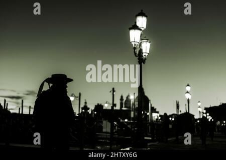 Atmosphère sombre, gondolier comme silhouette à l'heure bleue devant la lampe de rue éclairée, Venise, Vénétie, Italie Banque D'Images
