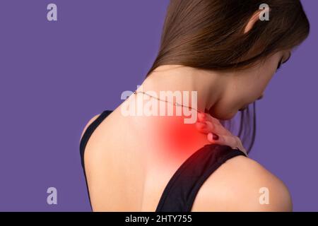 Vue arrière photo d'une jeune femme portant des vêtements de sport tout en faisant des exercices de forme physique a tiré un muscle d'épaule, santé corps fitness. Banque D'Images