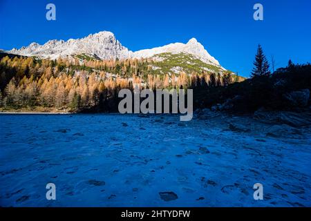 Les sommets de la cime del Laudo (à droite) et de la Cesta (à gauche), entourés de larches colorées et de pins en automne, vus au-dessus du lac gelé Sorapiss. Banque D'Images