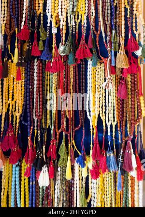 Grande collection de perles de prière aux couleurs magnifiques accrochées dans des rangées sur la tablette de présentation. Banque D'Images