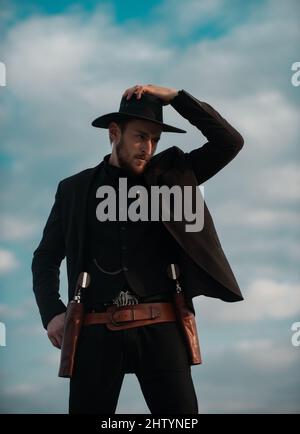 Shérif en costume noir et chapeau de cow-boy. Ouest sauvage, Ouest, homme avec revolver et munitions marshales millésimes. Banque D'Images