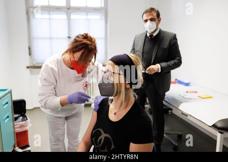 Freising, Allemagne. 03rd mars 2022. Anna Sixt (M) est vaccinée pour la première fois par un assistant médical au centre de vaccination de Freising avec le vaccin Nuvaxovid du fabricant Novavax. La jeune mère avait attendu sa vaccination jusqu'à présent, car elle allaitait encore sa fille. A droite, Klaus Holetschek (CSU), ministre bavarois de la Santé, observe la scène. Credit: Matthias balk/dpa/Alay Live News Banque D'Images
