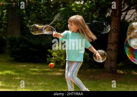 Joyeux joyeux enfant d'âge scolaire élémentaire, fille jouant avec des bulles de savon seul à l'extérieur, été, une bulle d'une personne qui s'éclate bonheur, avoir du plaisir, ch Banque D'Images