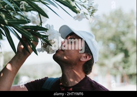 le voyageur authentique et mûr aime le parfum d'une fleur à la main, qui tient chaque jour un voyage d'été. concept de positiv sans stéréotypes Banque D'Images