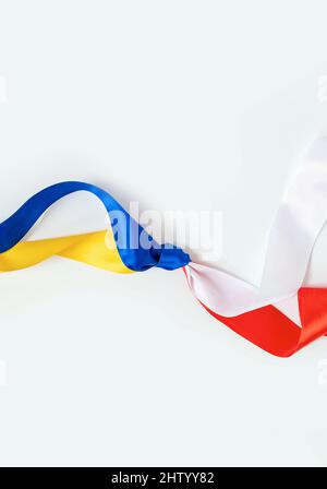 Deux drapeaux, la Pologne et l'Ukraine, noués sur fond blanc. L'amitié et le don de la Pologne à l'Ukraine pendant la guerre Banque D'Images