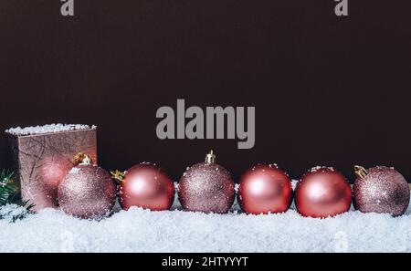 Boules de noël roses avec flocons de neige sur un mur brun foncé. Décor de Noël élégant. Carte de vœux tendance minimaliste. Joyeux noël et ha Banque D'Images